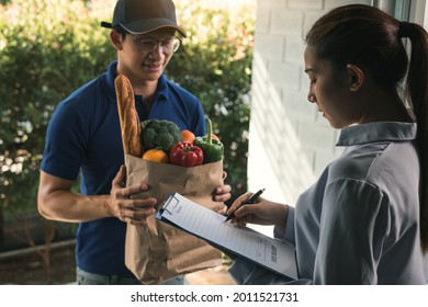 Asian woman is checking the product and signing the receipt on the order receipt through the online supermarket's home store.