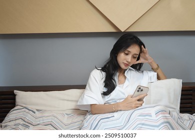 Asian woman checking work email or text on smartphone and a little annoyed - Powered by Shutterstock