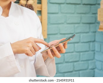 Una mujer asiática con uniforme de chef cocina en la cocina. Chef sonriente y feliz usando pantalla en blanco y mirando la cámara.