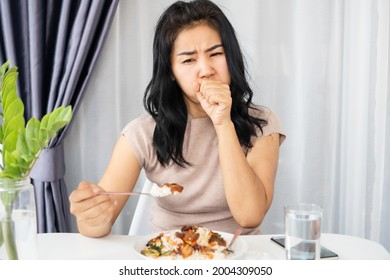 Asiatische Frau, die beim Essen erstickt wird, hält sich im Hals fest und versucht zu erbrechen oder Husten