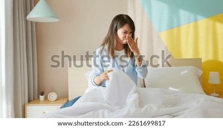 asian woman is cleaning up bedroom and bed quilt has bad smell