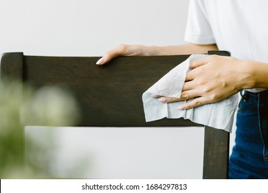 Asian Woman Cleaning Dining Chair With A Wipe. Close Up.