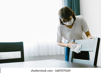 Asian Woman Cleaning Dining Chair With A Wipe.