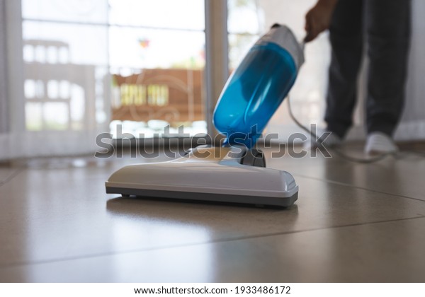 Asian woman cleaning the\
floor with vacuum cleaner in the living room. Woman doing chores at\
home.