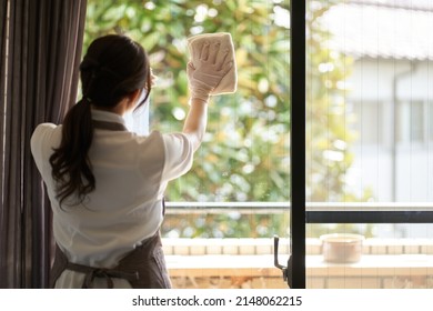 Asian woman cleaning the living room window