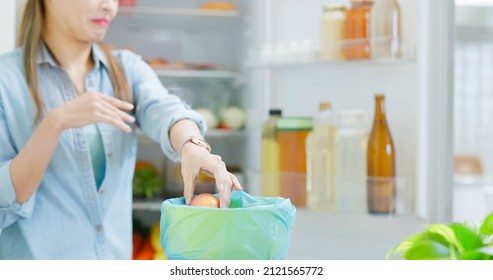 Asian Woman Is Cleaning Refrigerator And Pouring Food Waste Which Smell Bad Into Kitchen Bucket At Home