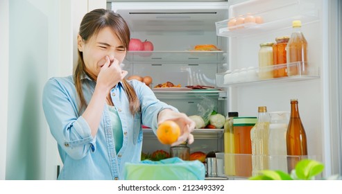 Asian Woman Is Cleaning Refrigerator And Pouring Food Waste Which Smell Bad Into Kitchen Bucket At Home