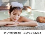 Asian woman with closed eyes resting in the hotspring bath