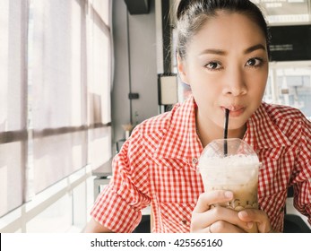 Asian Woman In Coffee Shop. Asian Woman Is Drinking Ice Coffee.