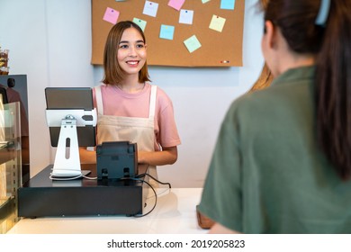 Asian woman coffee shop employee barista working at cafe. Smiling female waitress cashier taking order coffee and bakery from customer. Small business owner and part time job working concept - Powered by Shutterstock