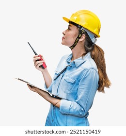 Asian woman construction worker in a yellow hard hat, holding a clipboard and walkie-talkie. The construction worker is focused, wearing a denim shirt. Construction worker safety gear.  - Powered by Shutterstock