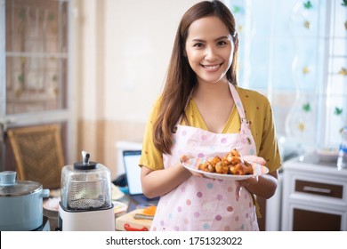 Asian woman Cooking lunch in the kitchen She shows fried chicken. - Powered by Shutterstock