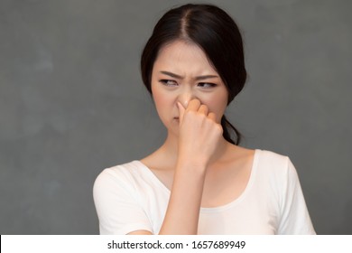 Asian Woman Covering Her Nose For Bad Smell, Concept Of Stink Thing, Bad Breath, Unpleasant Smell, Rotten Food, Odor, Body Bad Smell; Young Adult Chinese Asian Woman Model