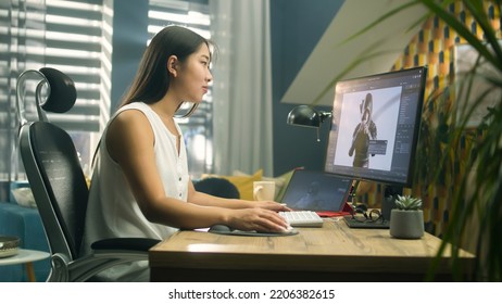 Asian woman creating 3D model of video game character in professional program using computer and digital tablet while working at home office