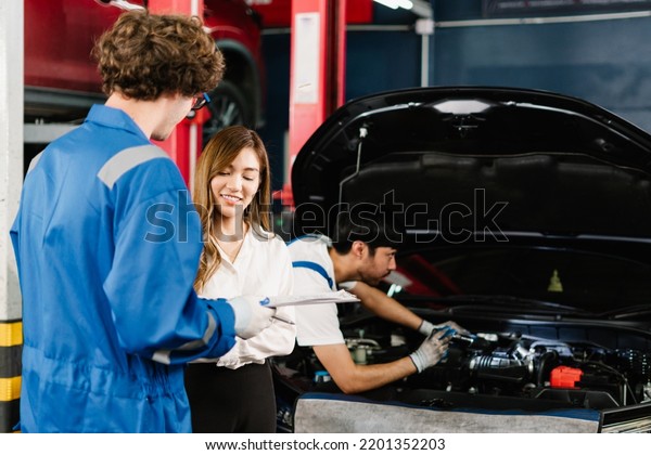 Asian woman customer and auto mechanic talking\
about her vehicle\'s check list and fixed items, Car Service Center\
and Maintenance at garage