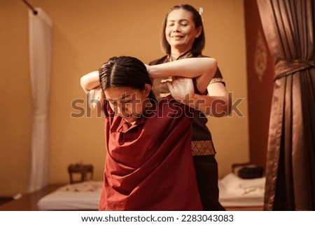 Asian woman customer get service Thai massage of stretching for treat painful from office syndrome with masseur in spa salon. Thai massage with masseur in spa salon.