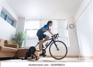 Asian woman cyclist. She is exercising in the house.By cycling on the trainer and play online bike games - Powered by Shutterstock