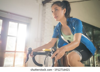 Asian Woman Cyclist. She Is Exercising At Home. She Is Playing Games In The Virtual World.