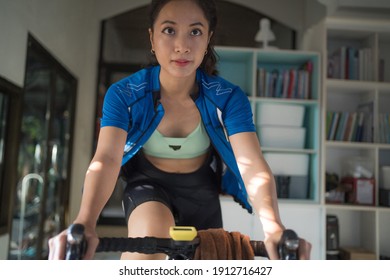 Asian Woman Cyclist. She Is Exercising At Home. She Is Playing Games In The Virtual World.