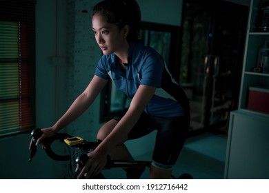 Asian Woman Cyclist. She Is Exercising At Home. At Night She Is Playing Games In The Virtual World.