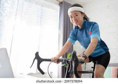 Asian Woman Cyclist. She Is Exercising At Home And Smile, Look At The Camera. 