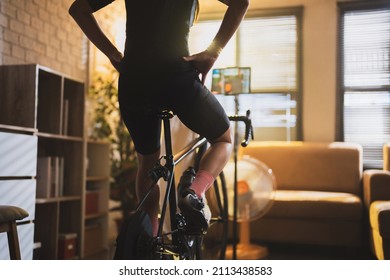 Asian woman cyclist. She is exercising in the house.By cycling on the trainer and playing online bike games at night  - Powered by Shutterstock