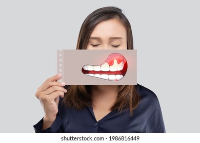 Asiatische Frau im dunkelblauen Hemd, die ein Papier mit dem gebrochenen Zahn-Cartoon-Bild seines Mundes auf grauem Hintergrund hält, Zahn verfallen, Das Konzept mit Zahnfleisch und Zähnen