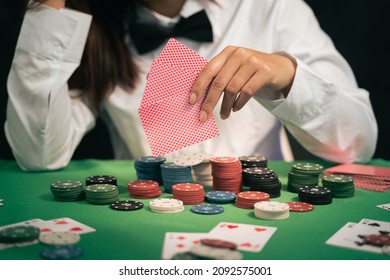 Asian Woman Dealer Or Croupier Shuffles Poker Cards In A Casino On The Background Of A Table,asain Woman Holding Two Playing Cards. Casino, Poker, Poker Game Concept