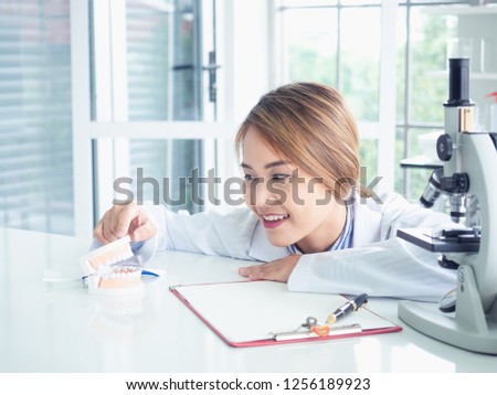 asian woman dentist looking on a jaw model