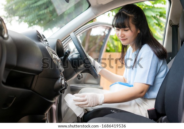 Asian woman disinfecting gear shift of car by\
disinfectant disposable wipes from box. Prevent the virus and\
bacterias, Prevent covid19, corona virus, Alcohol Sanitizer.\
Hygiene concept at home.