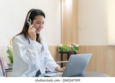Asian Woman Doctor In Headset Taking Calling On Her Headset Microphone Online For An Ache Patient
