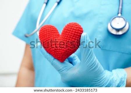 Asian woman doctor holding red heart for health in hospital.