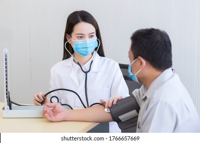 Asian Woman Doctor Listen Pulse (heart Rate) By Use Stethoscope Put On Foldable Joint Of A Man Patient And Pump Rubber Of A Blood Pressure Meter. Both Wear A Medical Face Mask At Hospital.