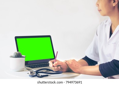 Asian Woman Doctor Looking on Laptop Computer Green Screen Writing Report of Patient Who Come to Make Health Check up at Hospital or Clinic. - Powered by Shutterstock