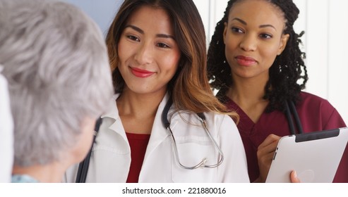 Asian Woman Doctor And Nurse Talking To Elderly Patient In Bed