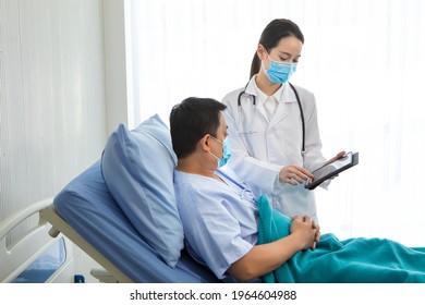 Asian Woman Doctor Talking With A Man Patient Who He Is On Bed