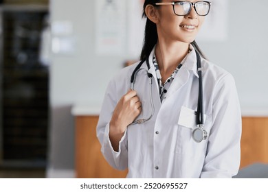 Asian woman, doctor and thinking with smile at hospital, lobby and vision for healthcare services. Person, medic and happy with stethoscope, perspective or insight for wellness with career at clinic - Powered by Shutterstock