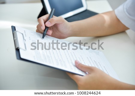 Asian woman Doctor working and using taking note information of patient in checklist paper on clipboard in medical room of hospital. Health care for people.