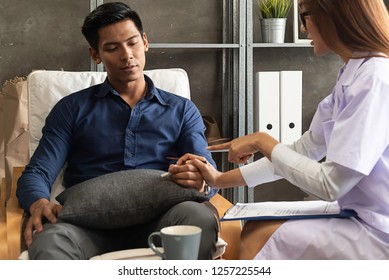 Asian woman doctor,gynecologist,psychiatrist consult and listen problem male patient who want to stop smoke ciigarette at relax room in hospital.
