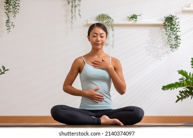 Asian Woman Doing Breathing Exercise Before Practice Yoga.Healthy Female Inhaling And Exhaling To Deep Breath Exercise For Control And Balance Life With Yoga Meditation Decrease Stress, Relax Her Mind