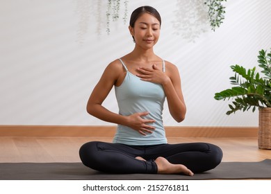 Asian woman doing breathing exercise before practice yoga.Healthy female inhaling and exhaling to deep breath exercise for control and balance life with yoga meditation decrease stress, relax her mind