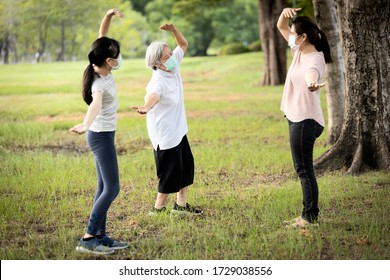 Asian Woman Is Doing Exercise Activity For The Old Elderly And Child Girl,family Workout,wearing Protective Mask Outdoor At Park,work Out Outside Home After Coronavirus Quarantine Or Covid-19 Lockdown