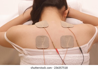 Asian woman is doing massage of electrical stimulation ( TENs ) for the back      