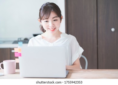 Asian Woman Doing Remote Work With Laptop At Dining Table At Home