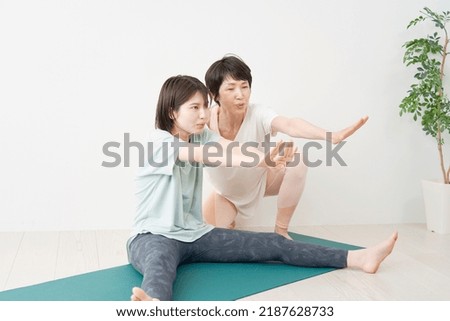 Asian woman doing yoga with a instructor at home