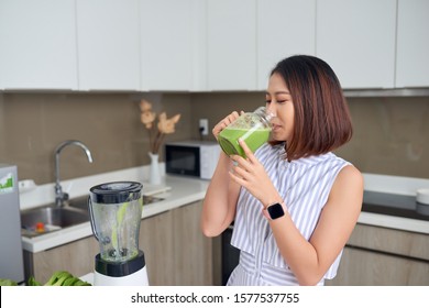 Asian Woman Drinking Smoothie In The Kitchen. Healthy Concept.