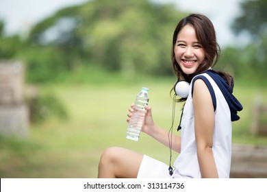 Asian Woman Drinking Water After Exercise At The Park. During The Summer