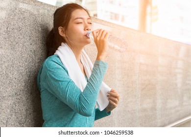 Asian Woman Drinking Water To Rehydrate To Avoid Heat Stroke After Running Outdoors In The Summer.