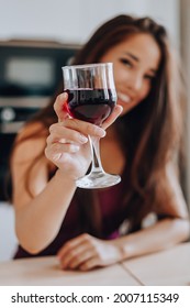 asian woman drinking wine in the kitchen at home