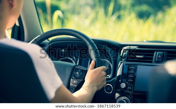 Asian\
woman driver driving off road car in the\
nature